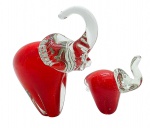 MURANO - 02 esculturas de diferentes tamanhos, representando um elefante adulto e um filhote, em vidro translúcido e vermelho (corpo dos elefantes). Medidas: 14 x 16 cm; 10 x 9 cm. Elefante maior com ínfimos bicados no dorso e na cauda; elefante menor com ínfimo bicado na tromba e bicados na base.