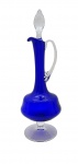 Licoreira em cristal translúcido e na cor azul cobalto, tampa em forma de gota, alça curva e bojo cilíndrico e achatado; base pedestal. Medidas: 40 x 14 cm. Com trincado na base do bojo.