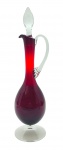 Licoreira em cristal translúcido e na cor rubi, tampa em forma de gota, alça curva e bojo oval; base pedestal. Medidas: 40 x 11 cm.