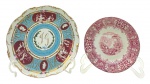 02 diferentes pratos decorativos em porcelana, sendo: 01 na cor rosa magenta, com selo de fabricação peruana, adornado na borda com padrões florais, vegetalistas e volutas, e em sua galeria central com cenário de arquitetura moura e com figuras em trajes mouros tradicionais; e 01 em porcelana multicolorida, de estilo clássico, decorado com medalhões contendo efígies, cenas com ninfas e personagens da mitologia greco-romana, detalhes em dourado e monograma na galeria central, sem marca de fabricante ou origem. Medidas: 21 cm (diâm.); 27 cm (diâm.). Prato peruano com craquelados superficiais e ínfimas manchas, devido à antiguidade da peça; prato maior com ínfimos desgastes na douração.