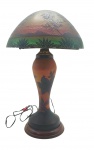 LUIZ OCTÁVIO RAVAGNANI (1962) - Abajur de mesa, de inspiração Art Nouveau, no formato cogumelo ("mushroom lamp"); cúpula em domo, em tons castanhos e verde, adornada com cenário lacustre, silhuetas de árvores e pássaros; haste de formato balaústre, adornada com motivos fitomórficos marrons sobre fundo âmbar; em pasta de vidro com gravação a ácido; sobre base circular de metal; haste assinada pelo artista RAVAGNANI, mestre vidreiro brasileiro nascido em Petrópolis. Medidas: 51 x 30 cm. Cúpula adaptada posteriormente, mantendo-se a integridade estética do conjunto. Não testado. Base da cúpula com ínfimos bicados.