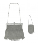 Conjunto com 01 antiga bolsa de mão em prata e 01 porta-níqueis, peso total: 209 g, com alça de corrente e decoração fitomórfica; trabalhados no estilo malha e com franjas na parte inferior. Medidas: 16 x 15 cm; 9 x 5 cm.