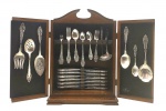 COMMUNITY (ONEIDA LTD.) - Faqueiro em metal espessurado à prata, com 86 peças, decoradas no estilo clássico no cabo com motivos florais, vegetalistas e volutas em relevo; facas com lâminas em aço inoxidável; organizados em armário de mesa em madeira nobre e com duas portas frontais. Fabricados pela tradicional empresa americana Oneida, fundada em 1899. Medidas (armário): 50 x 34 x 13 cm. Armário com arranhões e marcas.