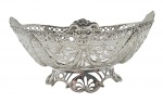 Centro de mesa oval em prata, peso: 200 g, adornado na borda com faces antropomórficas e no bojo com padrões fitomórficos vazados; base oval seguindo o padrão decorativo do restante da peça. Medidas: 18 x 13 x 8 cm.