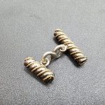 Abotoadura em ouro amarelo com prata, unidas por um elo em forma de oito.