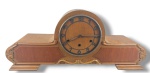 RELÓGIO, um (1) relógio carrilhão de mesa, estante ou cornija, da marca JUNGHANS (Gebr Junghans Uhrenfabrik foi fundada por Erhard Junghans com Franz Xaver em 1861), mecânico, mostrador com algarismos dourados e dois furos para dar corda (sinaliza a cada meia hora e hora cheia), gabinete no padrão Art Decor, confeccionado em madeira clara, entalhes vegetalistas com falhas na madeira, visor com ausência da marca e do vidro, aro metálico com sinais de oxidação, vendido no estado, não testado e  sem garantia de funcionamento, medindo 26x62,5x14,5cm.