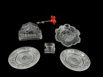 VIDROS, lote com seis (6) peças confeccionadas em vidro translúcido, sendo: A) 1 flor decorativa em vidro de Murano na tonalidade vermelha e translucida, medindo 15,5cm, B) 1 porta guardanapo com lapidação floral em baixo relevo, medindo 11,5x15x4,5cm, C) 1 cinzeiro em cristal SEVRES de origem francesa, bicado na borda, medindo 3x6x6cm, D) 1 petisqueira no feitio de folha, medindo 19,5x18cm, bicado na borda e E) 2 pratos para pão com moldagem perolada, vegetalista e fundo estrelado, medindo 15cm.