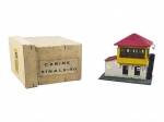 FERROMODELISMO, uma (1) cabine de sinaleiro para ferrorama, estrutura metálica, com base cenográfica, construção em dois pavimentos, telhado vermelho, paredes em tom claro, pavimento superior amarelo, janelas aplicadas e escada lateral. Acompanha caixa original identificada Cabine Sinaleiro, sinais de cola e uso, medindo 9x10x6,5cm.