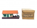 FERROMODELISMO, uma (1) estação ferroviária em miniatura, modelo Old Timer, em materiais distintos, com edificação na cor verde, telhado alaranjado, portas e janelas verdes, plataforma com pequenos acessórios e figura humana. Acompanha caixa original em papelão com inscrição Estação Old Timer. Peça usada, apresentando sinais de uso e sinais de cola, medindo 8x17x8,5cm.