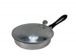 METAL PRATEADO, um (1) cata migalhas confeccionado em metal prateado, cabo em madeira torneada com pintura preta, pega da tampa cinzelada em elementos vegetalistas, pontos de oxidação e leve falha na pintura do cabo, medindo 6x28x15,5cm.