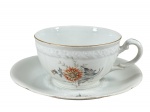 MZ Moritz Zdekauer (Produzida após 1918, ano da independência da Checoslováquia), uma (1) xícara para chá de coleção com seu respectivo pires, confeccionada em porcelana na tonalidade branca, decorada por flores e folhagens em policromia e vestígios de filete em ouro, medindo 5,5x12x9,5cm.