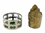 METAL PRATEADO e DOURADO, duas (2) peças, sendo: A) 1 porta copo em metal dourado, cinzelado por folhagens com bordas recortadas e vazadas, medindo 10x7cm e B) 1 porta garrafas em metal prateado com cinzelado de elefantes e elementos geométricos em vazados, fundo em vidro na tonalidade verde, medindo 5x9cm.