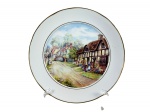 PORCELANA SCHMIDT, um (1) prato decorativo confeccionado em porcelana na tonalidade branca, com pintura de paisagem inglesa com figuras em policromia e filetes em ouro com falhas na douração, medindo 26cm de diâmetro.
