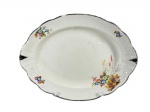 J&G Meakin (Foi uma importante fábrica de cerâmica inglesa fundada em 1851, em Hanley, Staffordshire, Inglaterra), uma (1) travessa oval confeccionada em faiança inglesa na tonalidade branca, decorada por flores e folhagens em policromia, bordas em ondulações com filete e realces em ouro com falhas na douração, sinais de craquele e leves marcas do tempo, medindo 37,5x28,5cm.