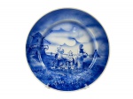 FAIANÇA SANTA CRUZ, um (1) prato decorativo confeccionado em faiança vitrificada na tonalidade branca, decorado por paisagem holandesa com figuras na tonalidade azul, sinais de craquele, medindo 32,5cm de diâmetro.