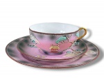 PORCELANA SATZUMA, um (1) trio para chá confeccionado em porcelana na tonalidade rosa com decoração de montanhas, arvoredos e pagodes em policromia e relevo com realces em ouro, sendo: A) 1 xícara para chá com seu respectivo pires, medindo 4,5x10,5x8,5cm e B) 1 prato para bolo, medindo 17,5cm, leves falhas na pintura.