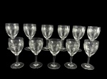 CRISTAIS, onze (11) taças para vinho confeccionadas em cristal translucido com lapidação de guirlanda de cachos de uva e folhas de parreira em baixo relevo, haste cilíndrica, apoiada sobre base circular, medindo 15x6,5cm.