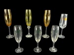 VIDROS, lote com sete (7) taças flutes confeccionadas em vidro de modelos, tamanhos e decorações distintas, sendo 3 nacaradas em tom dourado, medindo 24x4,5cm (1 bicada na borda), 1 com decoração 2000 em ouro, medindo 21x4,5cm e 3 da marca EISENBAHM LUST, medindo 20x4,5cm.