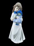 LLADRÓ (Valência, Espanha, desde 1953), uma (1) escultura confeccionada em porcelana espanhola na tonalidade branca representando menina com boneca, apresentando colado no corpo, vide foto, medindo 21m.
