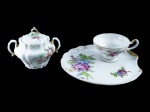 PORCELANAS, lote com duas (2) peças, sendo: A) 1 açucareiro confeccionado em porcelana na tonalidade branca, decorado por flores e folhagens em policromia e realces em ouro, bicado na borda e na pega, medindo 10x12,5x7cm e B) 1 xícara biscoiteira com seu respectivo pires, confeccionado em porcelana na tonalidade branca com pintura de flores e folhagens em policromia com realces em ouro, apresenta bicado na borda, medindo 6x11,5x9cm.