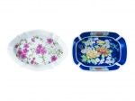 PORCELANAS, duas (2) petisqueiras confeccionadas em porcelana na tonalidade branca, sendo: A) GUILLEN (ESPANHA), 1 oval, decorada por flores e folhagens em policromia com recortes na borda, medindo 13,5x9,5cm e B) ECHO (TAKAHASHI SAN FRANCISCO), 1 retangular, elementos geométricos sobre fundo azul, flores e folhagens em policromia, medindo 12,5x9cm.