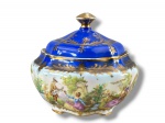 PORCELANA DP 541, uma (1) biscoiteira confeccionada em porcelana na tonalidade branca com pintura na tonalidade azul, ricamente decorada por cenas galantes em rica policromia com realces vegetalistas e filetes em ouro, apresentando falhas na douração e colado na peça, medindo 15x14cm.
