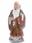 ESCULTURA ORIENTAL, uma (1) escultura confeccionada em biscuit com vestes vitrificadas representando Shou Xing, o Deus da Longevidade, esmaltado em rica policromia, medindo 24cm de altura.