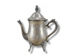 METAL PRATEADO, um (1) bule para café confeccionado em metal espessurado a prata, corpo liso, bico, alça e pés cinzelado por elementos florais e vegetalistas em relevo, apoiado sobre 4 pés, medindo 22x20x9cm.