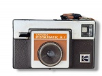 FOTOGRAFIA, KODAK INSTAMATIC X-1, uma (1) câmera fotográfica vintage, em corpo retangular de material plástico, nas cores preto, prata e cobre, com lente frontal fixa, visor lateral, marca Kodak aplicada e alça superior oxidada, marcas de uso, não testada e sem garantia de funcionamento, vendida no estado da foto.