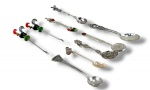 METAL PRATEADO, lote com nove (9) peças confeccionadas em metal prateado composto por pequenas colheres de souvenir, mexedores e garfinhos/espeto decorativos, com cabos ornamentados, aplicações esmaltadas coloridas, motivos de galo, cruz, medalhão, relevos florais e frisos geométricos.