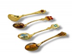METAL DOURADO, quatro (4) pequenas colheres souvenir de coleção confeccionadas em metal dourado, com cabos ornamentados e terminais decorados com brasões e aplicações esmaltadas coloridas, incluindo modelos com cenas turísticas pintadas nas conchas, como Acropolis, Budapest e outras localidades.