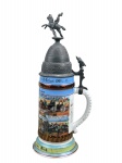 PORCELANA, um (1) tankard confeccionado em porcelana na tonalidade branca, (Reservistenkrug) do 1º Batalhão do 19º Regimento de Artilharia de Campo ("1. Thüringisches Feldartillerie-Regiment Nr. 19"), baseado em Erfurt, comemorativo das manobras imperiais de 1906, adornado com pintura esmaltada com cenas de batalha, tampa em pewter encimado por soldado a cavalo, apresenta mossa na tampa e restauro na base, medindo 33cm de altura.