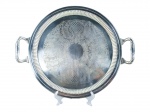 METAL PRETEADO, uma (1) bandeja redonda confeccionada em metal espessurado a prata com rico cinzelado de elementos vegetalistas e florais, borda em gomos e alças vazadas, medindo 46x37cm.
