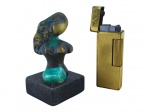 ESCULTURA e ISQUEIRO, lote com duas (2) peças, sendo: A) 1 escultura representando nu feminino confeccionado em bronze, apoiada sobre base em marmore preto com incrustação de ágata verde, medindo 7,5cm e B) 1 isqueiro da manufatura DUNHILL confeccionado em metal dourado com sinais de uso e oxidações, acondicionado em caixa original, necessitando revisão, medindo 6,5x2,5cm.