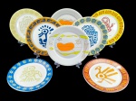 PORCELANAS, oito (8) pratos rasos confeccionados em porcelana na tonalidade branca da marca Spoleto  Culinária Italiana, edição limitada da série Tesouro Perdido, artista Eduardo Garcia, com decoração colorida de motivos estilizados e figuras de inspiração lúdica/étnica, em tons variados. Peças com inscrição no verso Spoleto Culinária Italiana, Edição Limitada, Série: Tesouro Perdido, Artista: Eduardo Garcia, resistentes a micro-ondas e lava-louças, medindo 25cm de diâmetro.