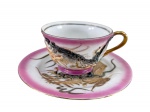PORCELANA SATZUMA, uma (1) xícara de coleção com prato para para bolo, pintura degrade em tom rosa com decoração de dragão em relevo e policromia com filetes em ouro c/ falhas na douração, medindo 6x11x9cm e prato 15,5cm. Não acompanha píres.