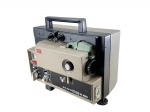 ELETRÔNICO, um (1) projetor de filmes antigo da marca ELMO, modelo ST-180 M-O 2-Track, para filmes 8mm, com sistema sonoro, controles frontais de volume, balanço, frame e loop, corpo em tons bege e preto, alça superior para transporte, acompanhado de caixa original em papelão, berço de isopor, cabo de força, carretel e acessório Bonum para emenda/prensagem de filme S8, sinais de uso, medindo 28x31x18cm, funcionando, sem garantias futuras.