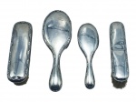 PRATA DE LEI, conjunto de toucador com quatro (4) escovas com capa confeccionadas em PRATA DE LEI, contrastada 800, cinzeladas por caneluras e folhagens, apresentam sinais de uso, mossas e 1 escova com desgastes na borda, maior escova medindo 20cm e menor 15cm. Peso total bruto 304,3g.