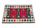 TAPEÇARIA, uma (1) tapeçaria com padronagem geométrica de inspiração étnica/oriental, em tons de vermelho, vinho, creme, verde, azul, amarelo e preto, com faixa central de losangos e formas estilizadas, borda clara com losangos coloridos, medindo 92x140cm.