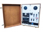 SOM, um (1) gravador/reprodutor clássico 3 em 1 da marca Akai, modelo X-2000SD Cross-Field, combinando em um único aparelho os formatos de fita de rolo/open reel, fita cassete/compact cassette e cartucho 8-track. Peça de fabricação japonesa, acondicionada em gabinete/estojo de madeira com tampa articulada, painel frontal metálico, carretéis superiores, compartimento para cartucho, comandos de play, rewind, fast forward, pause/start, seleção de canais, controles de volume/tone e entradas para microfone/fone. Parte traseira com etiqueta original, indicação AC100-240V, 50-60Hz, 60W. Apresenta marcas de uso, leves falhas na madeira e pontos de oxidação, não testado e sem garantia de funcionamento, medindo 47x24x35cm.