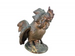 ESCULTURA  - Uma (1) escultura em porcelana representando galo, confeccionada em material rígido, com acabamento policromado em tons envelhecidos de marrom e dourado.Peça com detalhes em relevo nas penas, crista, asas e base, medida : 15 x 23 cm , desgastes na pintura