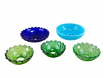 VIDRO, conjunto composto por cinco (5) bobeches em vidro colorido, em diferentes tonalidades de verde, azul cobalto e azul claro, com formatos arredondados, bordas trabalhadas e relevos decorativos em estilo concheado. Azul clara possui pequeno defeito de fabricação , medidas : 3 x 8,5 e 4,5 x 12 cm , possui bicados nas bordas .