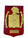 COLECIONISMO, uma (1) placa comemorativa de parede, em formato de escudo, confeccionada em madeira , com aplicação de brasão em metal dourado, trazendo escudo heráldico em relevo, elmo na parte superior e faixas laterais com inscrição em espanhol Más vale honra sin barcos que barcos sin honra. Acompanha placa metálica inferior gravada En recuerdo de la visita  D.D. Méndez Núñez. Medida : 29 x 18 cm