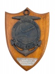 COLECIONISMO, Uma (1) placa comemorativa de parede, em formato de escudo, confeccionada em madeira ,  com aplicação em metal escurecido/patinado em formato de âncora e medalhão naval, com inscrição Patria Honor y Mar e referência ao General Urdaneta F-23. Possui cena em relevo com embarcação e submarino/torpedo, além de placa metálica inferior gravada Al Defensora (F-41) como recuerdo UNITAS XXIX  Pto Rico 26 Jul 88. Medida : 26 x 19 cm