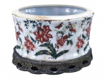 PORCELANA ORIENTAL, um (1) cachepot confeccionado em porcelana oriental na tonalidade branca, esmaltagem craquelada, decorado por flores e folhagens em policromia, base oval em resina com decoração vegetalista em vazados, bicado na borda, medindo 14x21x16cm.