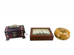 DIVERSOS, lote com três (3) caixas porta joias de modelos, tamanhos e decorações distintas, sendo: A) 1 em plástico com caixa musical e interior espelhado, medindo 9x12x8cm, B) 1 em madeira com tampo com pintura de embarcação sobre vidro, medindo 4x16x11,5cm e C) 1 redonda confeccionada em madeira com patina na tonalidade bege, decorado por flores e folhagens em policromia, apresentando falhas internas, medindo 6x11cm.