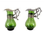 VIDROS e METAL PRATEADO, par (2) de galhetas confeccionadas em vidro na tonalidade verde, corpo bojudo, guarnição em metal  espessurado a prata com cinzelado de cacho de uvas, folhas de parreira e elementos vegetalistas em vazados, medindo 12,5cm de altura, leves falhas na prateação.