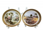 PORCELANA L DEPOS, dois (2) pratos decorativos confeccionados em porcelana na tonalidade branca, representando cenas campestres/europeias com personagens, animais, construções e paisagens em policromia com espessa faixa em ouro com elementos vegetalistas em relevo, medindo 24cm de diâmetro.