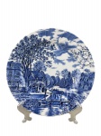 JOHNSON BROTHERS, um (1) prato decorativo confeccionado em faiança inglesa na tonalidade branca, decorado por cena campestre com casarios em monocromia na tonalidade azul, medindo 25cm.