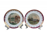 PORCELANA REAL, par de pratos decorativos em porcelana, com bordas em tom vinho e rica ornamentação dourada, reservas centrais com paisagens campestres pintadas à mão em relevo, representando moinho à beira dágua e chalé em cenário montanhoso , medida : 19 cm , um deles com falha na pintura .